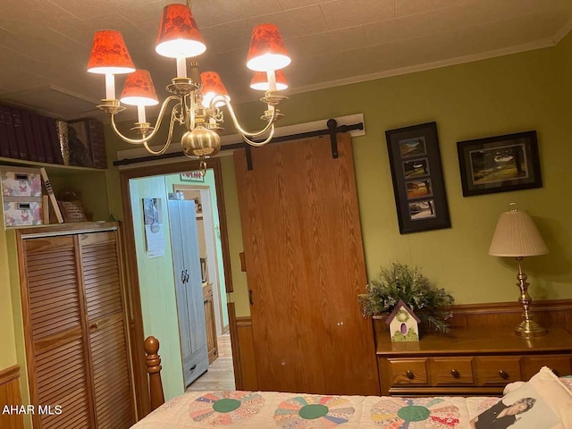 bedroom with a barn door, light wood-type flooring, crown molding, and an inviting chandelier