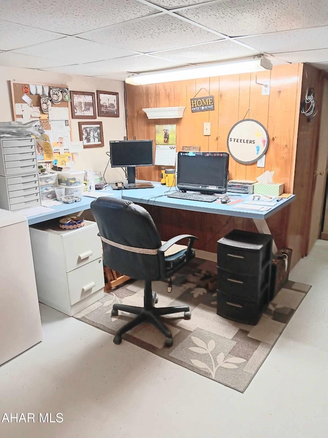 office space featuring finished concrete floors, wood walls, and a paneled ceiling