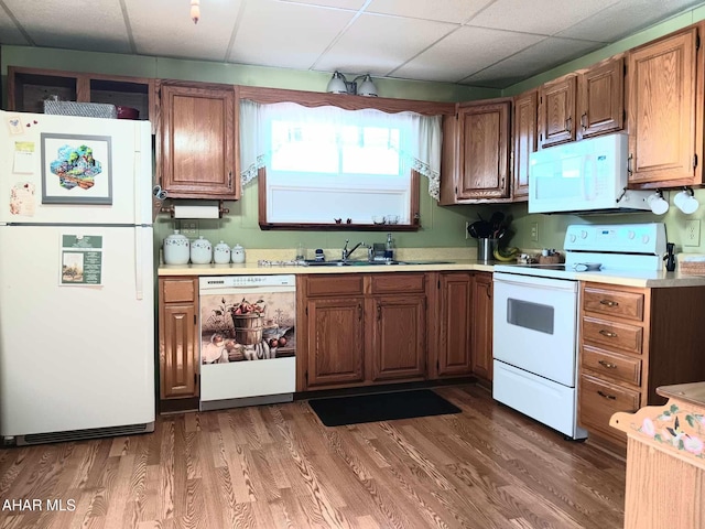 kitchen with white appliances, wood finished floors, light countertops, and a sink