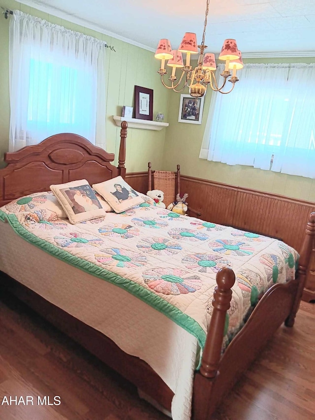 bedroom featuring a notable chandelier, wood finished floors, and ornamental molding