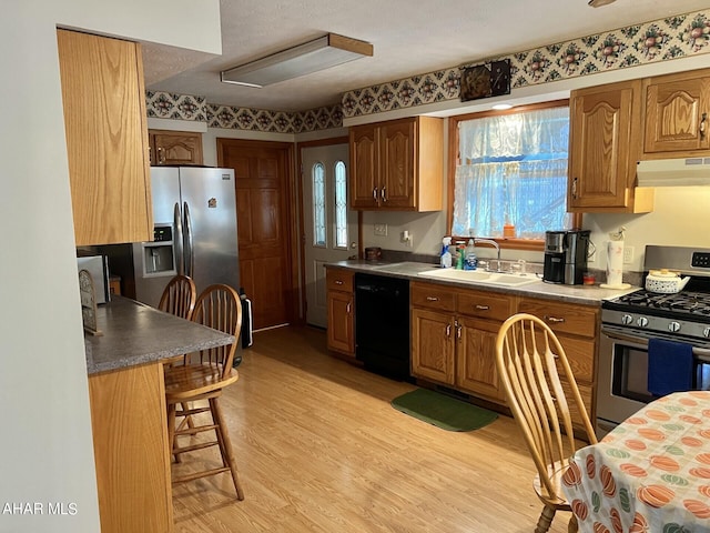 kitchen featuring sink, stainless steel appliances, a kitchen breakfast bar, light hardwood / wood-style flooring, and a textured ceiling