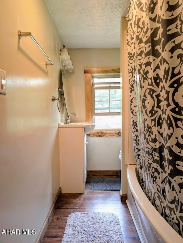 bathroom featuring vanity, a textured ceiling, hardwood / wood-style flooring, and shower / washtub combination