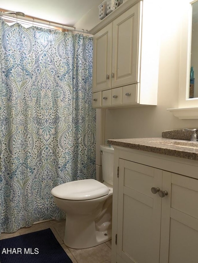 bathroom featuring tile patterned floors, curtained shower, vanity, and toilet