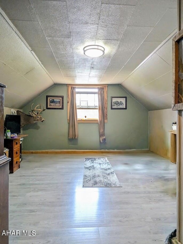 bonus room with vaulted ceiling, a textured ceiling, and light hardwood / wood-style flooring