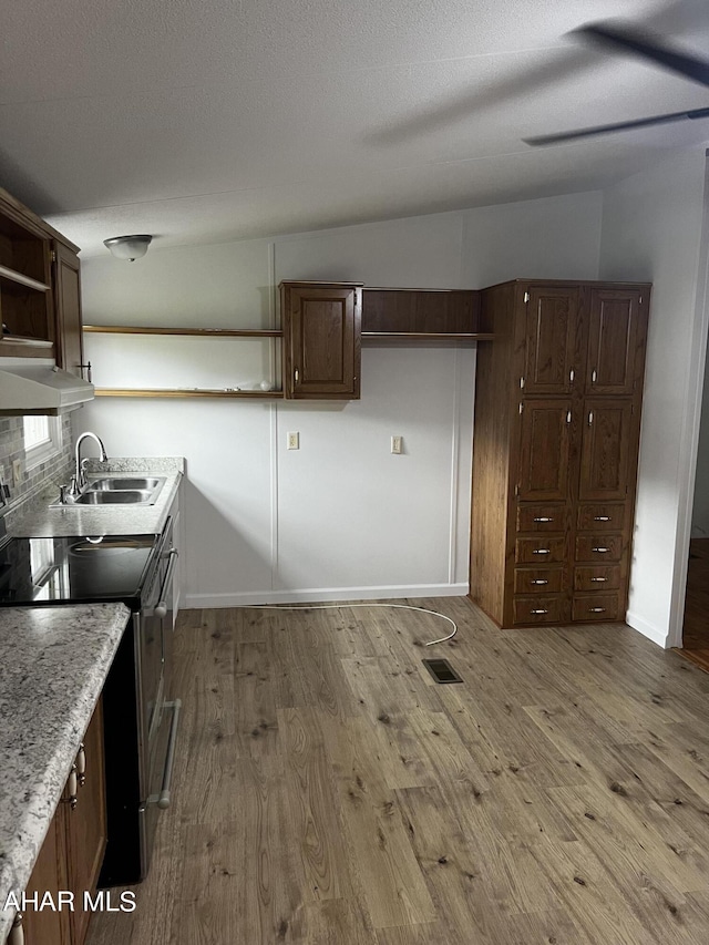 kitchen with sink, extractor fan, vaulted ceiling, stainless steel range with electric cooktop, and light wood-type flooring