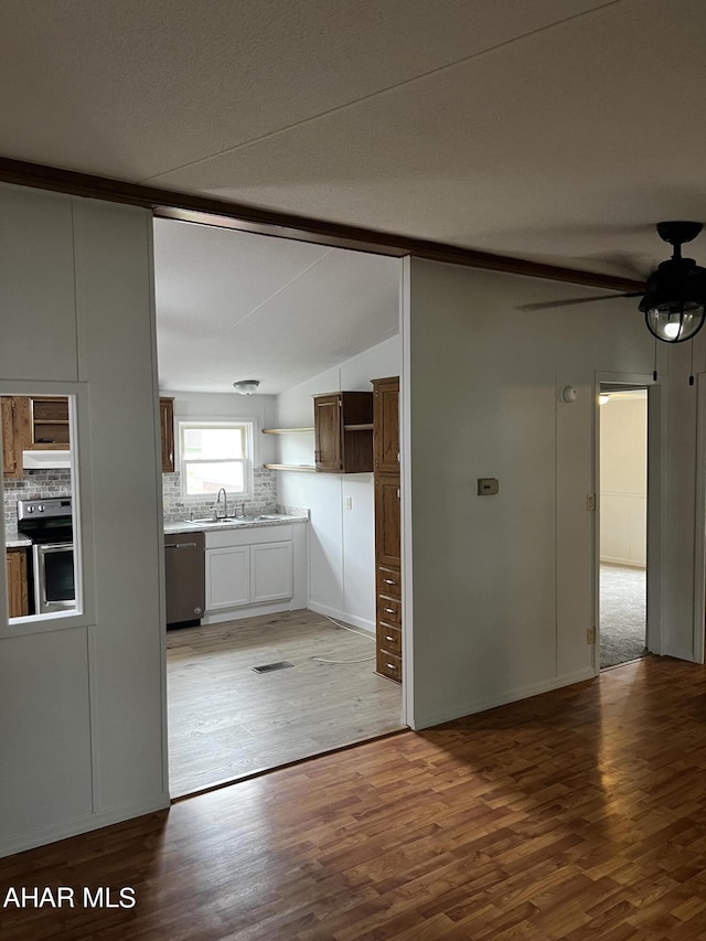 kitchen featuring backsplash, hardwood / wood-style flooring, lofted ceiling, and appliances with stainless steel finishes