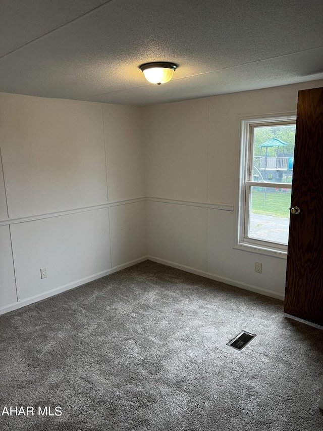 carpeted spare room featuring a textured ceiling