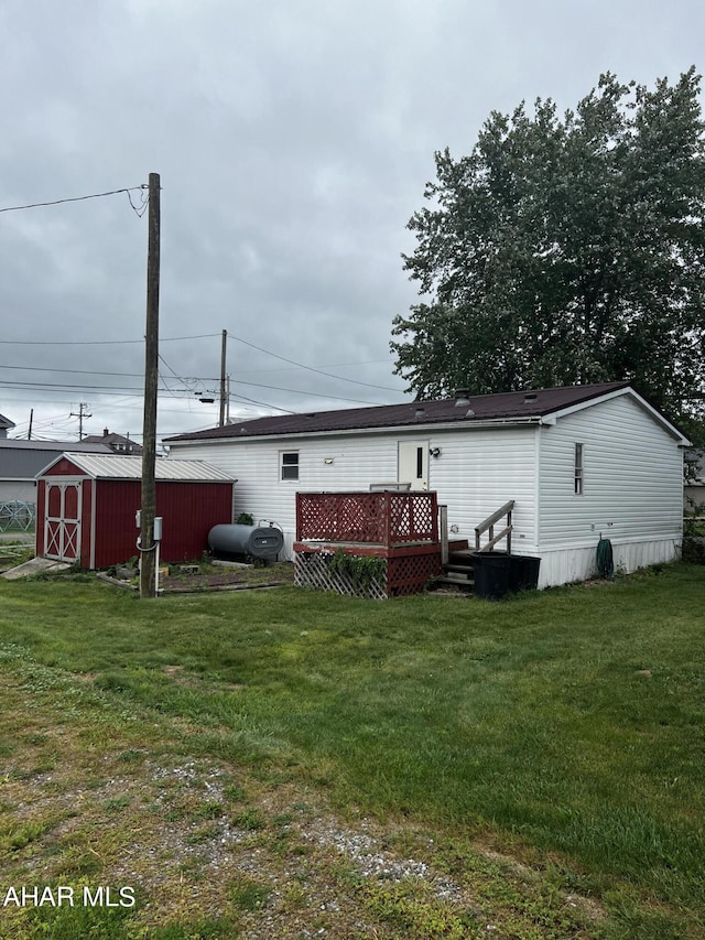 back of house with a shed, a deck, and a lawn