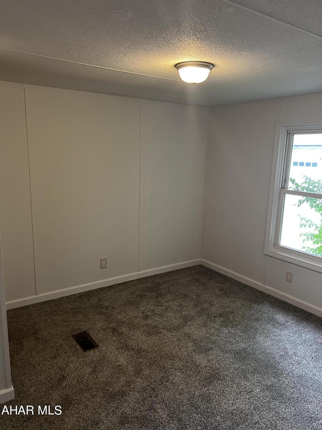 carpeted empty room with a textured ceiling