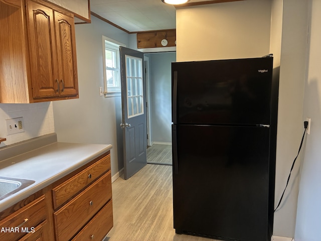 215 N 10th Ave, Altoona, PA 16601 - kitchen with freestanding refrigerator, light wood-type flooring, decorative backsplash, brown cabinets, and ornamental molding