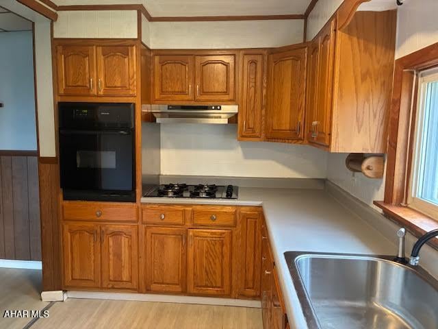 215 N 10th Ave, Altoona, PA 16601 - kitchen featuring black oven, under cabinet range hood, gas stovetop, brown cabinetry, and ornamental molding