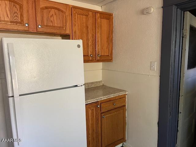 1008 21st Ave, Altoona, PA 16601 - kitchen with freestanding refrigerator, brown cabinetry, and wainscoting
