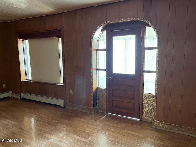 1008 21st Ave, Altoona, PA 16601 - foyer entrance with light wood-type flooring, a baseboard heating unit, wooden walls, and arched walkways