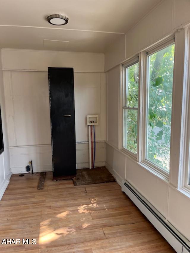 1008 21st Ave, Altoona, PA 16601 - empty room featuring a baseboard heating unit, healthy amount of natural light, light wood-style flooring, and a decorative wall