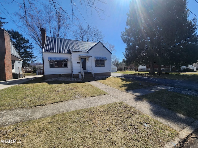 view of front of home featuring a chimney, metal roof, and a front yard