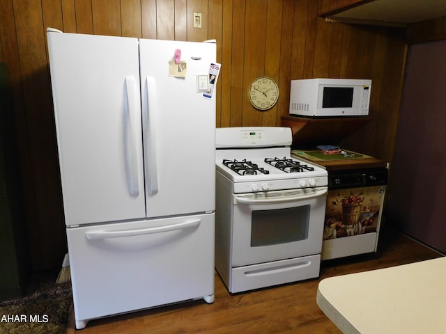kitchen with white appliances, wood walls, and wood finished floors