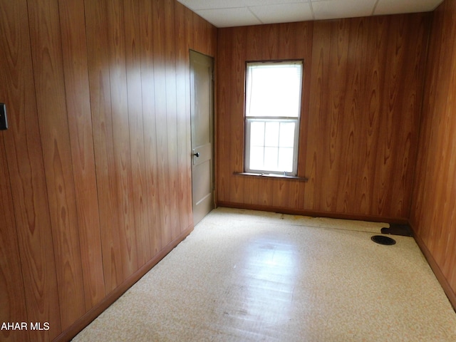 unfurnished room with wooden walls and baseboards