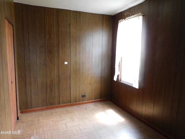 unfurnished room with healthy amount of natural light, wooden walls, and baseboards