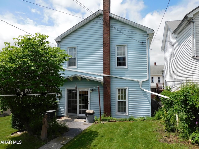 back of house with a yard and a chimney