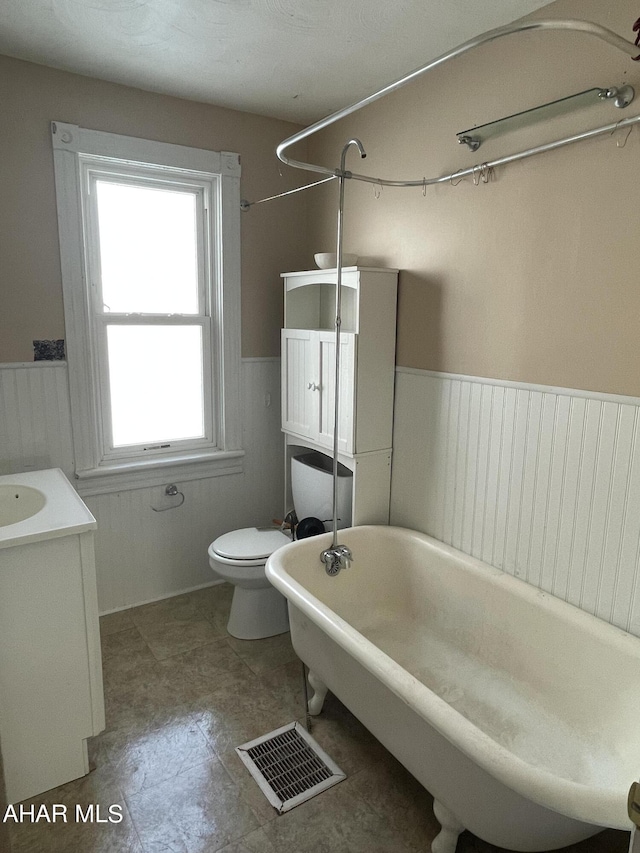 bathroom with vanity, a bath, and toilet