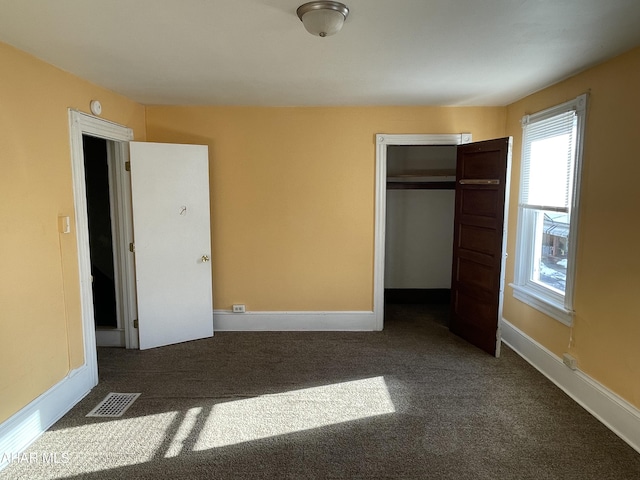 unfurnished bedroom with dark colored carpet and a closet