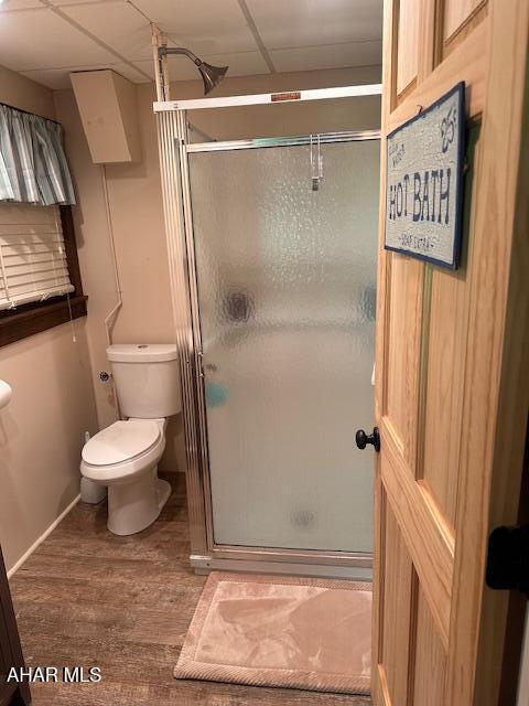 5168 Black Log Rd, Orbisonia, PA 17243 - bathroom with wood finished floors, toilet, a shower stall, a paneled ceiling, and baseboards