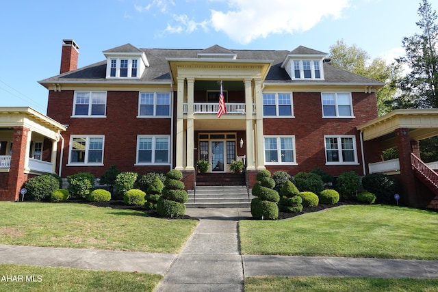 view of front facade featuring french doors, a balcony, and a front lawn