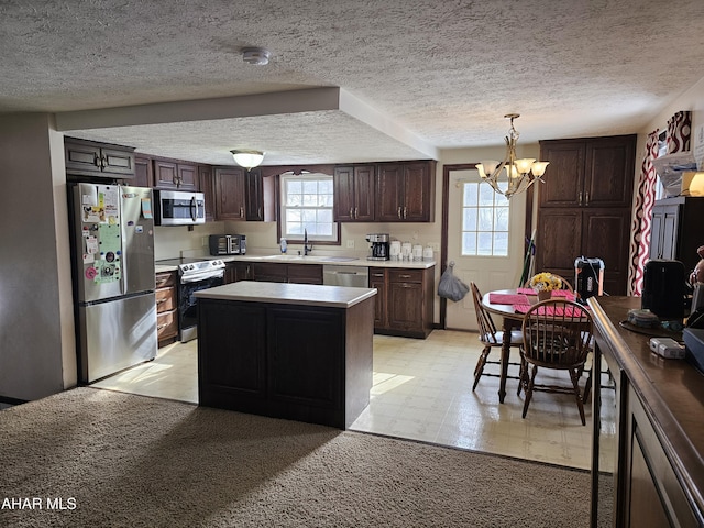 kitchen with hanging light fixtures, stainless steel appliances, an inviting chandelier, a textured ceiling, and a kitchen island