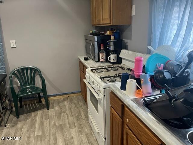 kitchen with light wood-type flooring, sink, and white gas range