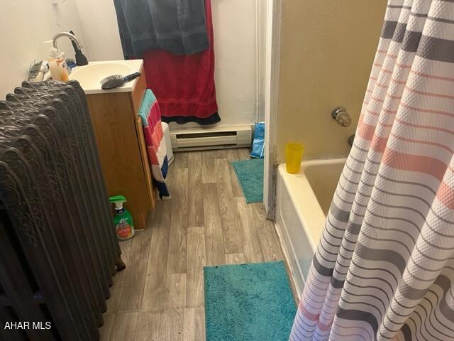 1004-08 17th Ave, Altoona, PA 16601 - bathroom featuring baseboard heating, wood-type flooring, vanity, and shower / bath combo with shower curtain