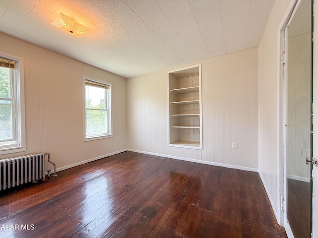 346 Lower Snake Spring Rd, Everett, PA 15537 - empty room featuring radiator heating unit, built in shelves, wood-type flooring, and wood walls