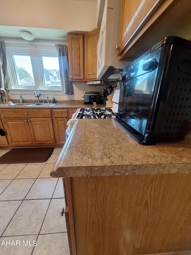 kitchen with light tile patterned flooring, white appliances, and sink