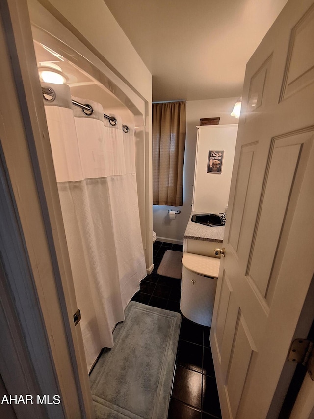 bathroom featuring tile patterned flooring, curtained shower, toilet, and sink