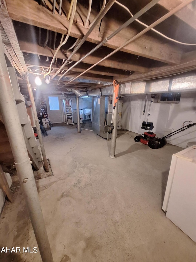 basement featuring white refrigerator and heating unit