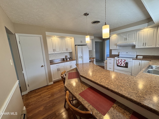 kitchen featuring white appliances, white cabinetry, hanging light fixtures, and dark wood-type flooring