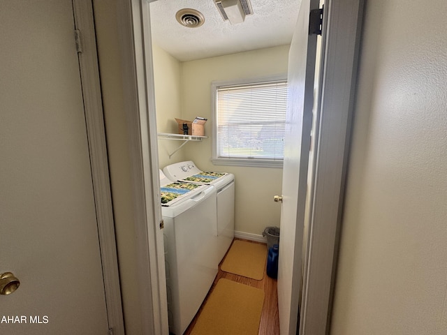 laundry area featuring hardwood / wood-style floors, a textured ceiling, and separate washer and dryer