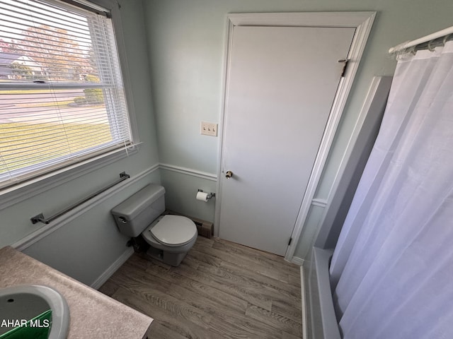 full bathroom featuring wood-type flooring, vanity, toilet, and shower / tub combo with curtain