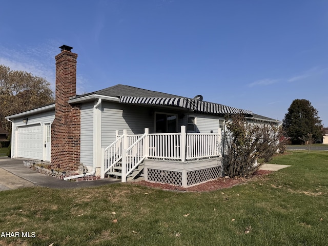 rear view of house with a garage, a deck, and a lawn