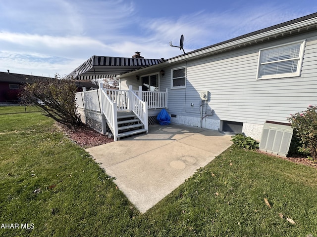 back of property with a yard, a patio area, and a wooden deck