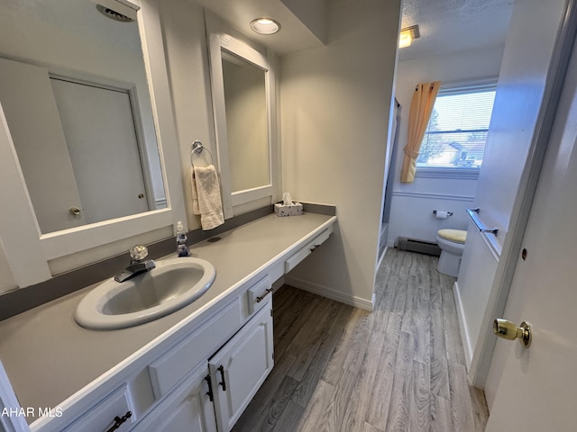 bathroom featuring hardwood / wood-style floors, vanity, toilet, and baseboard heating