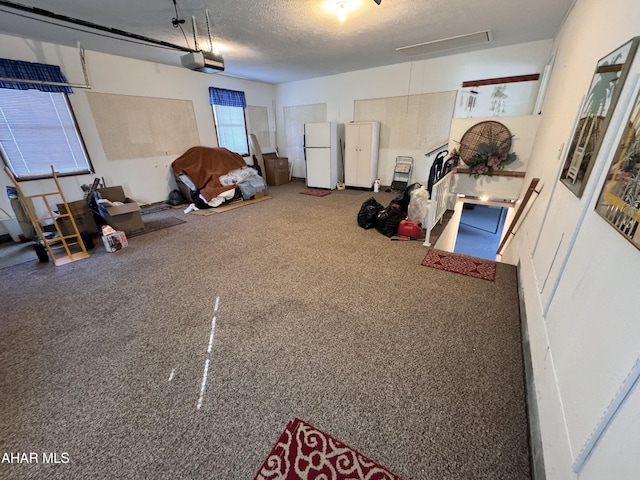 garage featuring white fridge and a garage door opener