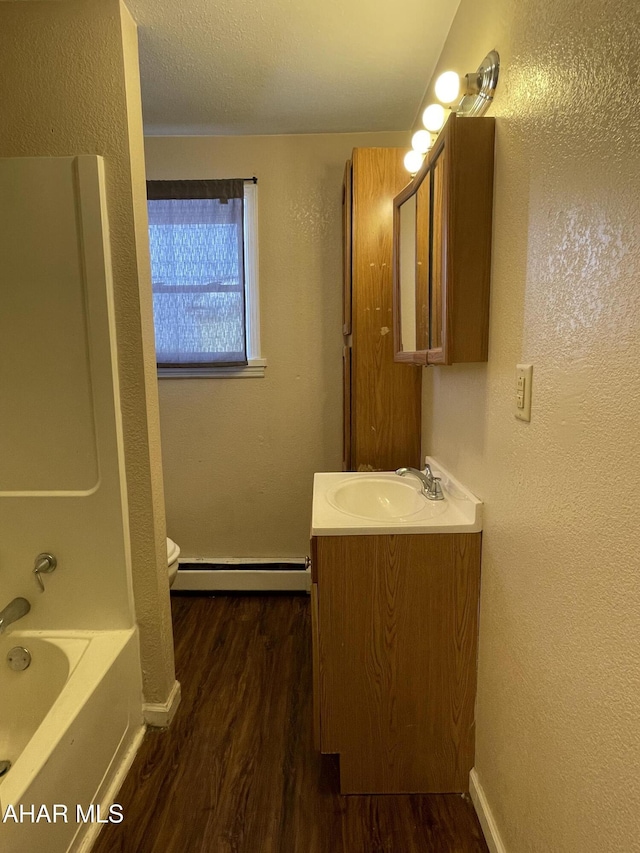 full bathroom with vanity, baseboard heating, shower / bathing tub combination, hardwood / wood-style floors, and toilet