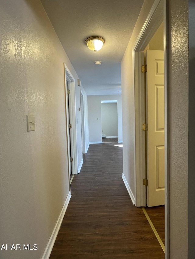 corridor featuring a textured ceiling and dark wood-type flooring