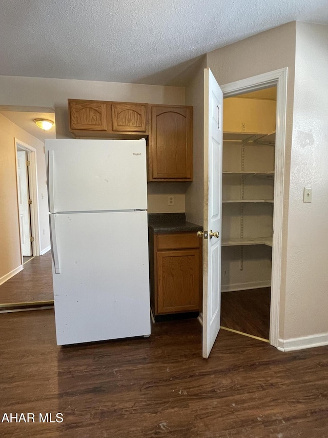 kitchen with a textured ceiling, white refrigerator, and dark hardwood / wood-style floors