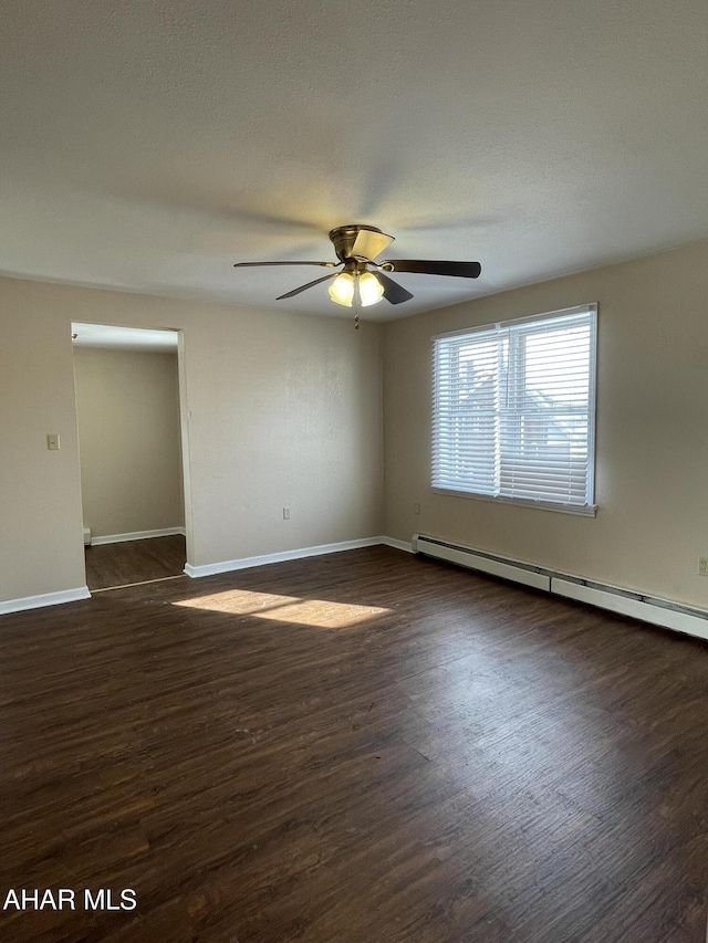 spare room featuring baseboard heating, ceiling fan, and dark hardwood / wood-style floors