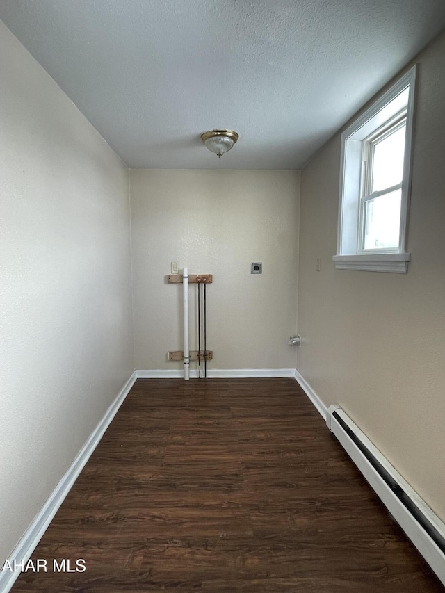 laundry room with electric dryer hookup, a textured ceiling, dark hardwood / wood-style flooring, and a baseboard heating unit