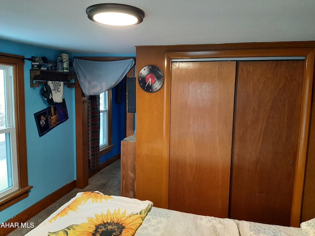 bedroom featuring a closet, multiple windows, and dark colored carpet