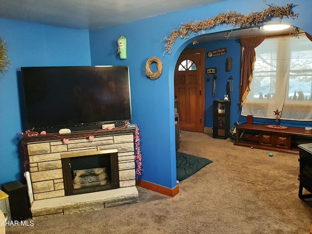 living room with a stone fireplace and carpet flooring