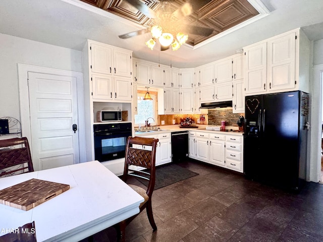 kitchen featuring an ornate ceiling, light countertops, white cabinets, under cabinet range hood, and black appliances