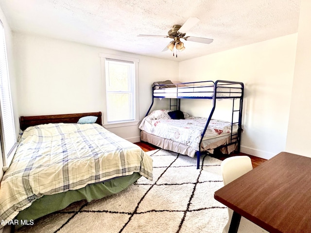 bedroom with a textured ceiling, baseboards, and wood finished floors